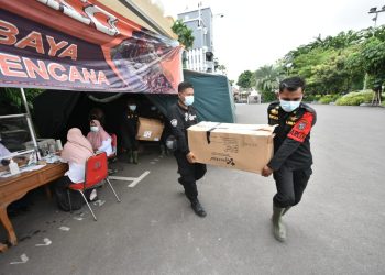 Dua personel BPB Linmas menggotong bantuan yang akan dinaikkan truk untuk dikirimkan untuk korban bencana ke Jember.