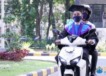 Lukman Ali, wisudawan dari Departemen Manajemen Bisnis yang hadir  secara drive thru dengan mengendarai motor listrik ITS GESITS pada Wisuda  ke-124 ITS.