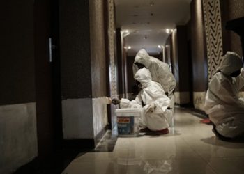 Dengan mengenakan baju hazmat, petugas melakukan perbaikan sejumlah fasilitas di Hotel Asrama Haji (HAH), Sukolilo.