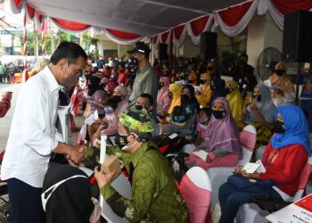 Presiden RI Joko Widodo menyerahkan bantuan sosial secara simbolis kepada warga penerima manfaat di Pasar Tambahrejo, Surabaya.