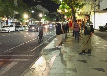 Personel Satpol PP Kota Surabaya menjaga kawasan Jalan Tunjungan setelah membubarkan kegiatan ‘Tunjungan Fashion Week’ yang berlangsung pada Minggu (24/7) malam.