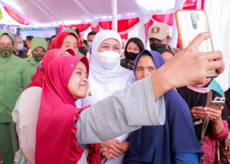 Gubernur Jawa Timur Khofifah Indar Parawansa berswafoto dengan warga di sela kegiatan penyerahan kunci rumah yang telah direhabilitasi.