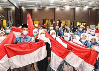 Gubernur Jawa Timur Khofifah Indar Parawansa berfoto bersama usai membagikan bendera merah putih kepada jemaah haji kloter SUB-38 di Asrama Haji Sukolilo Surabaya.
