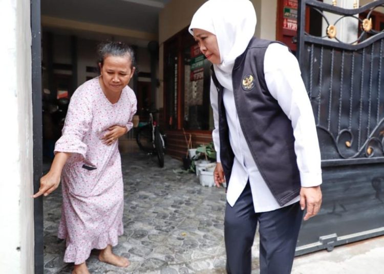 Seorang warga memberitahukan ketinggian banjir di rumahnya kepada Gubernur Jatim Khofifah Indar Parawansa.