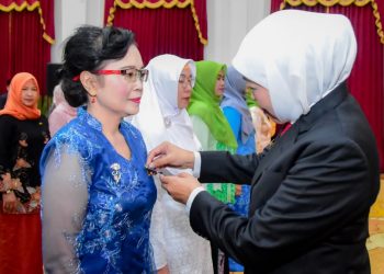 Momen saat Gubernur Jawa Timur Khofifah Indar Parawansa menyematkan Tanda Kehormatan Republik Indonesia Satyalencana Karya Satya kepada salah satu guru di gedung Negara Grahadi.