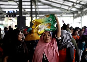 Seorang warga memanfaatkan Gerakan Pangan Murah Nasional yang digelar di Pasar Induk Surabaya Sidotopo (PISS) dengan membeli beras.