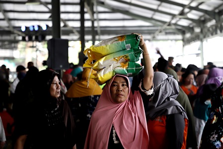 Seorang warga memanfaatkan Gerakan Pangan Murah Nasional yang digelar di Pasar Induk Surabaya Sidotopo (PISS) dengan membeli beras.