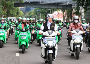 Gurbernur Jawa Timur Khofifah Indarwati yang sedang berkendara dengan mitra ojek online dalam rangka penandatangan Kepgub ojek online dan taxi online.