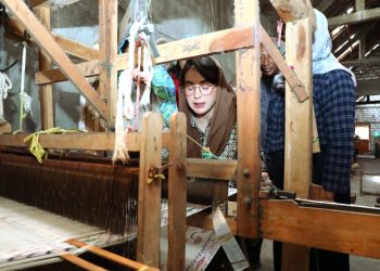 Ketua Dekranasda Jawa Timur Arumi Bachsin Emil Dardak mencoba alat tenun batik dalam kunjungannya ke sentra tenun dan batik di Gresik.