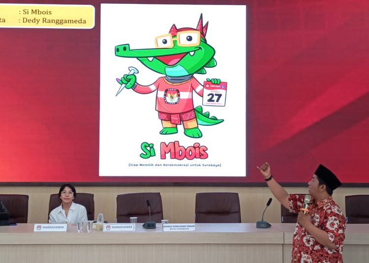 Komisioner KPU Surabaya Subairi dengan latar belakang maskot Pilwali Surabaya bernama ‘Si Mbois’.