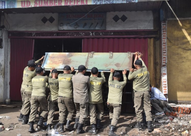 Sejumlah personel Satpol PP Surabaya meminggirkan lapak PKL di Pasar Dupak Rukun dalam upaya pengembalian fungsi jalan di kawasan tu.