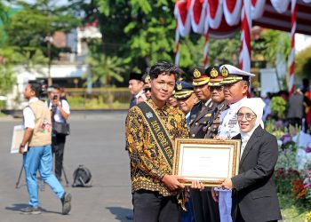 Penyerahan piagam penghargaan kepada salah satu generasi pemuda di momen peringatan Hari Sumpah Pemuda di halaman Balai Kota Surabaya.