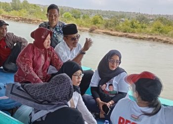 Tri Rismaharini menumpangi perahu saat meninjau meninjau lokasi titik banjir di Kabupaten Sampang.