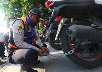 Personel Dishub Surabaya menggembok roda sepeda motor yang parkir di trotoar di depan Grand City Mall, Jalan Gubeng Pojok.