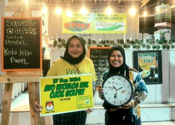 Salah satu pembeli Kedai Ketan Punel mendapatkan suvenir dari KPU Jatim.