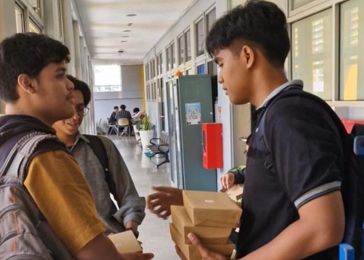 Bima Saputra (kanan) saat menjajakan nasi ayam geprek jualannya kepada teman-temannya di kampus ITS.