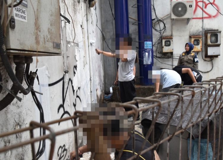 Pelaku vandalisme disanksi melakukan pengecatan kembali pada tembok yang dicorat-coret.