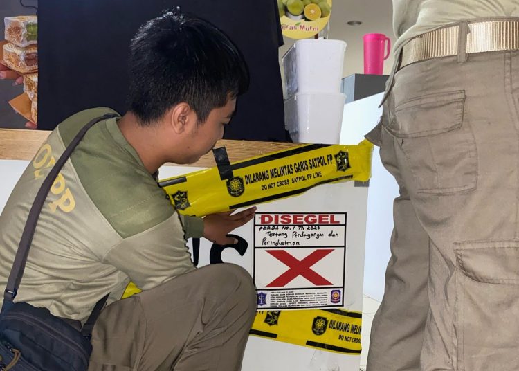 Personel Satpol PP Surabaya melakukan penyegelan stan es krim di salah satu pusat perbelanjaan di Surabaya Barat.
