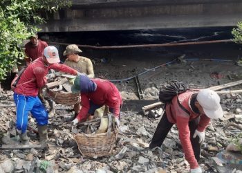 Tim satgas banjir melakukan pembersihan sampah di saluran air.