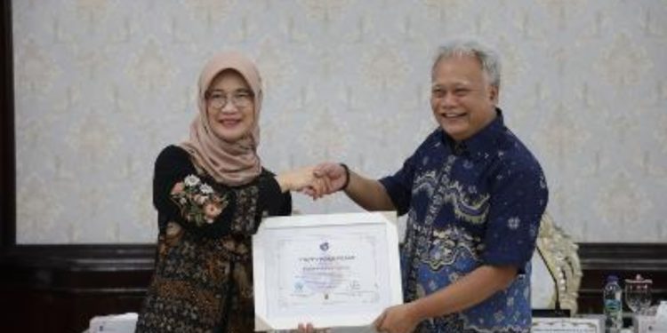 Deputi Bidang Koordinasi Kementerian Koordinator Bidang Pembangunan Manusia dan Kebudayaan (Kemenko PMK), Woro Sri Hastuti Sulistyaningrum  menyerahkan penghargaan kepada Sekretaris Daerah (Sekda) Kota Surabaya, Lilik Arijanto.